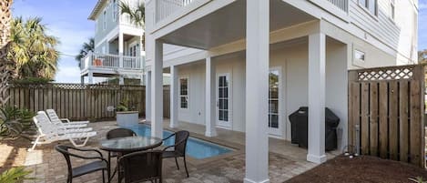 A two-story house with a covered patio, a swimming pool, and outdoor furniture.