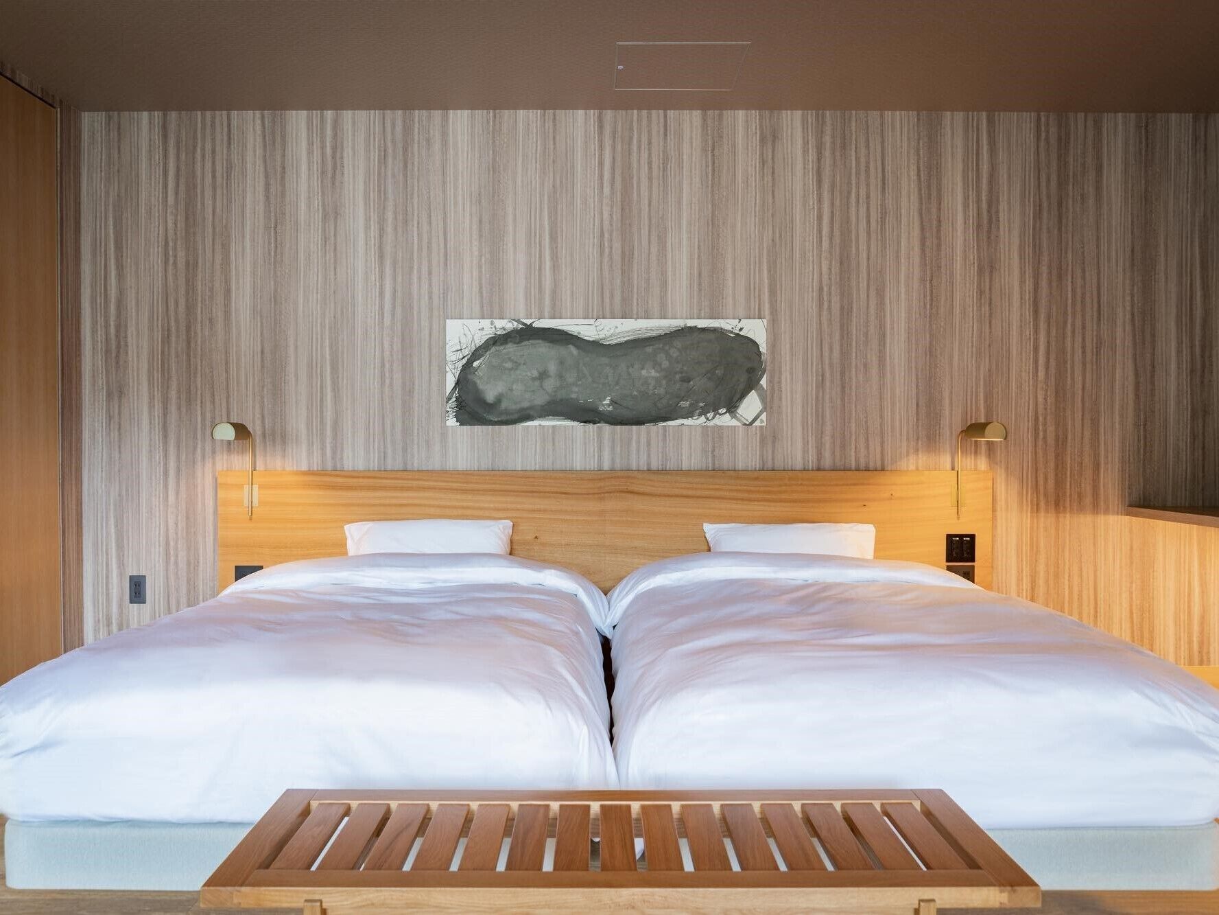 Una cama doble con cabecera de madera, dos mesitas de noche y un cuadro abstracto colgado en la pared.