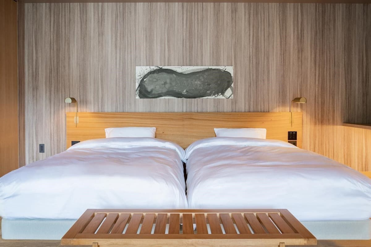 A double bed with a wooden headboard, two bedside tables, and a wall-mounted abstract painting.