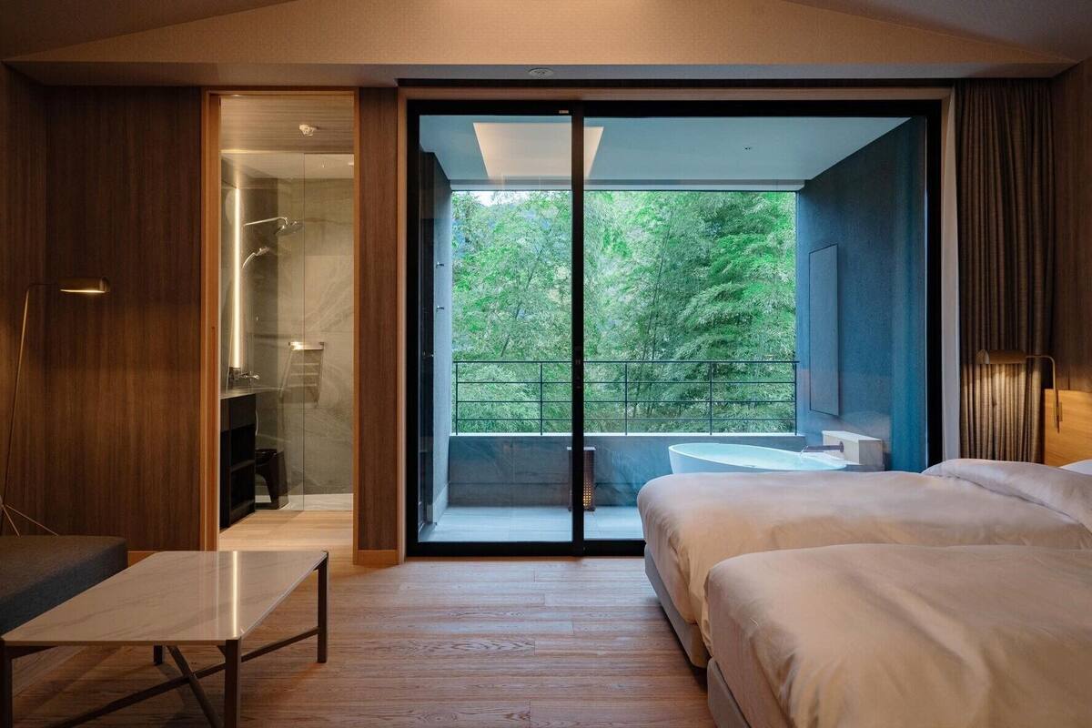 Una camera da letto moderna con un'ampia porta scorrevole in vetro che dà su un balcone, un comodino e un letto.