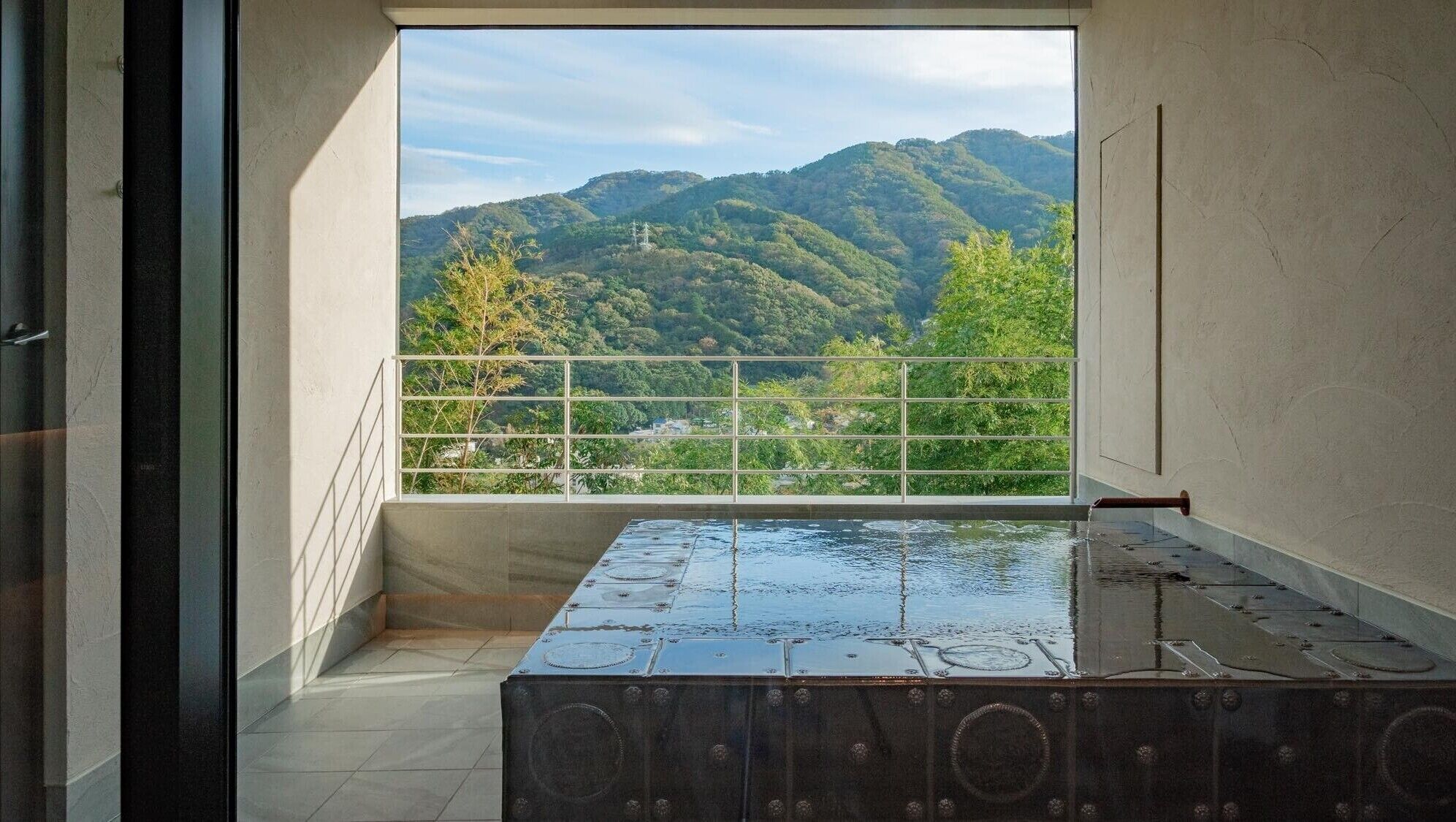 Una habitación con vista a un paisaje montañoso a través de una ventana con barandilla de metal.