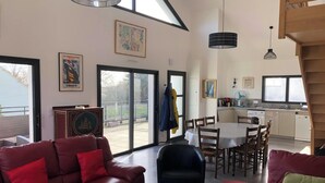 A spacious living area with a red leather sofa, a glass coffee table, and a dining table with chairs. There is a kitchen area with modern appliances and a large window providing natural light. - Homerez - House in Baden (Baden)