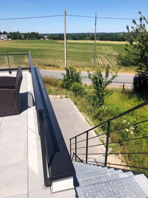 A view from a balcony overlooking a rural landscape with fields and a road.
