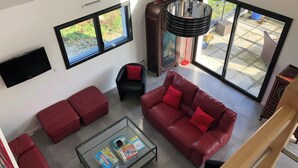 A modern living room with a glass coffee table, red sofas, and large windows offering a view of the outdoors. - Homerez - House in Baden (Baden)