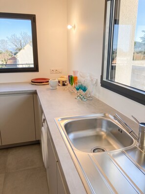 Een moderne keuken met een roestvrijstalen spoelbak, een raam en een aanrecht met verschillende spullen.