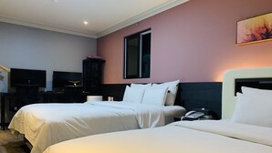 Et hotelværelse med to senge, et skrivebord med computer og et fjernsyn.