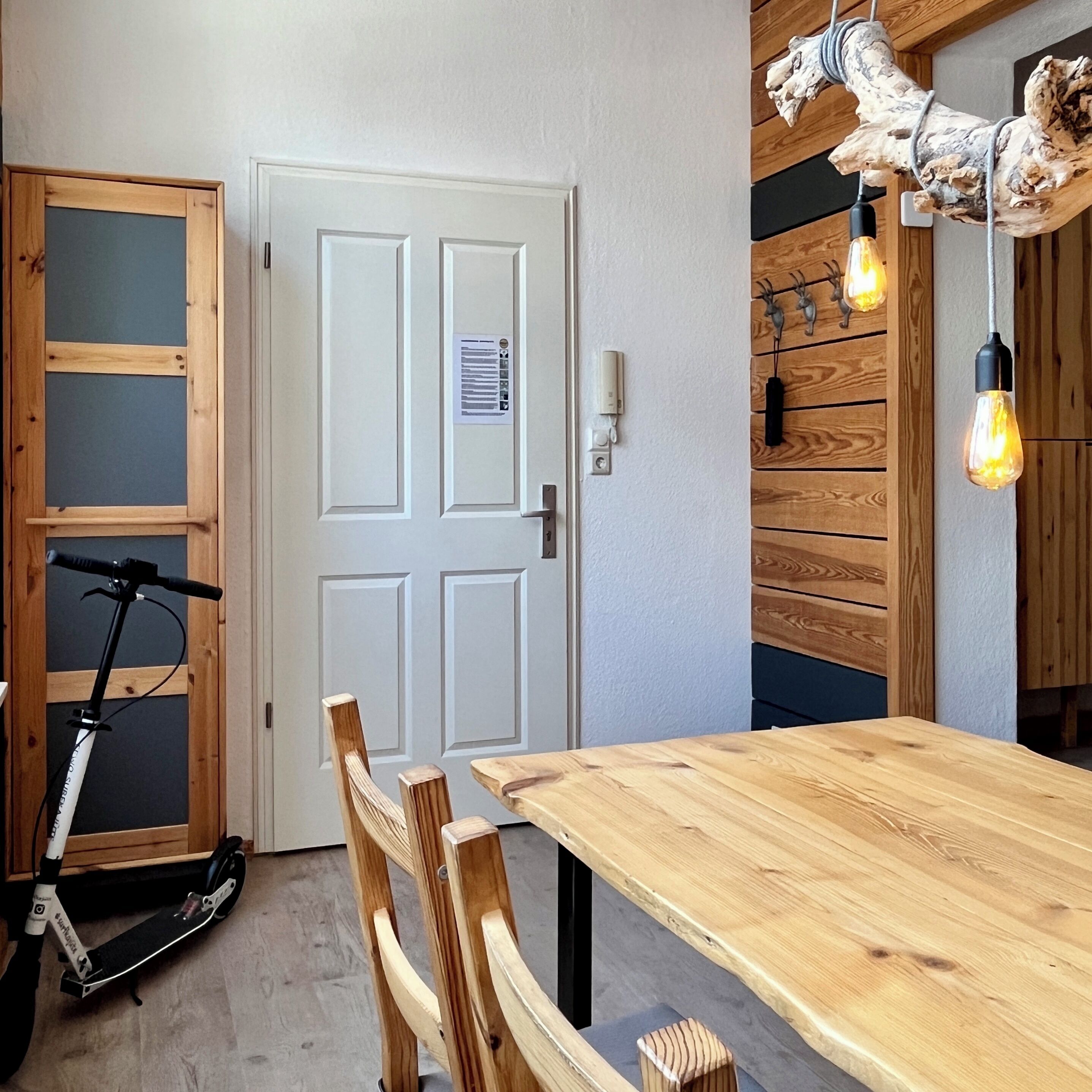 Una habitación con una mesa de comedor de madera, una moto y una puerta con un aviso.
