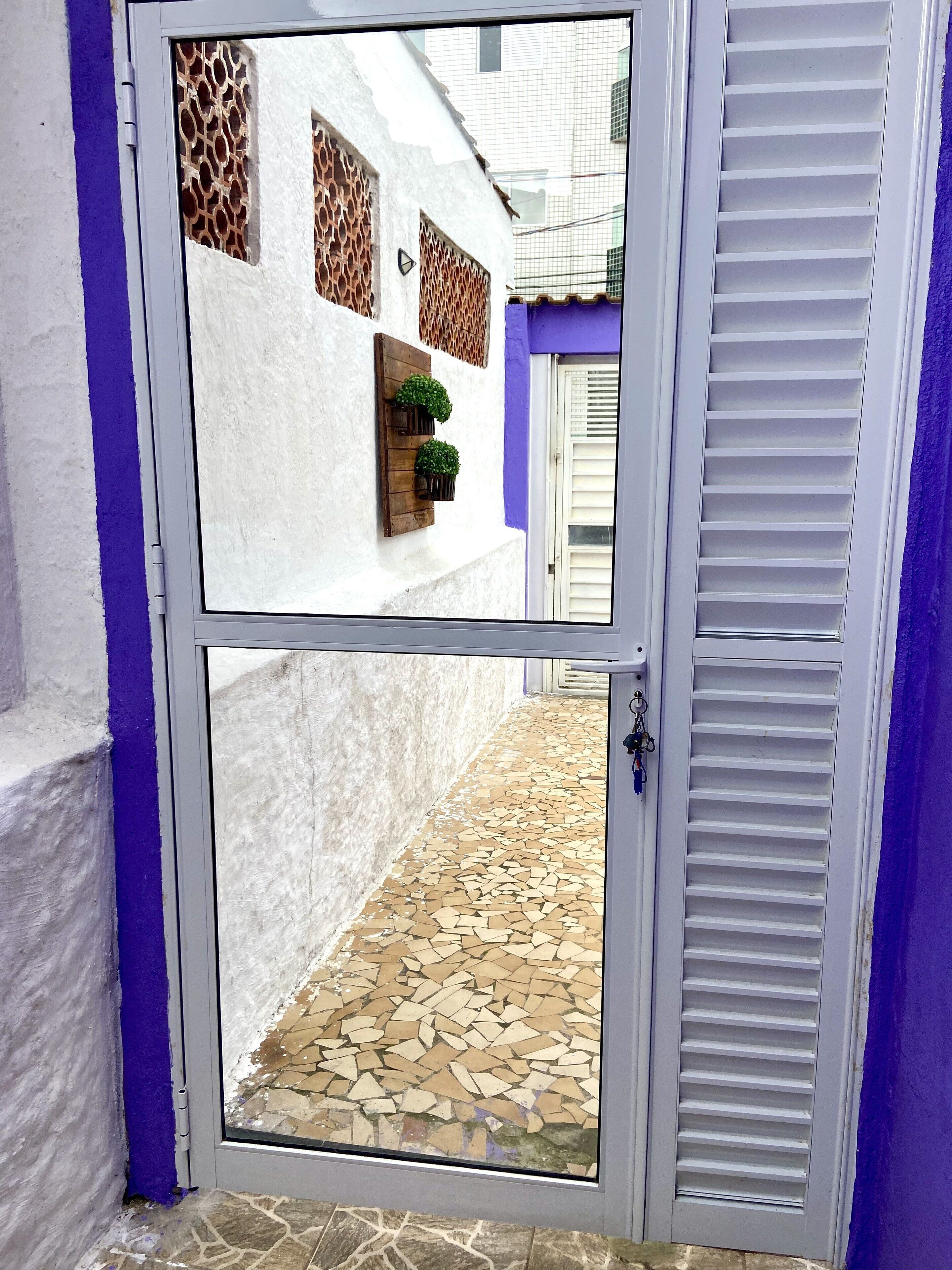 A white door with a glass panel, a wooden door frame, and a purple wall.