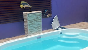 Ein rechteckiges Whirlpool mit Holzterrasse, einem blauen Pool und Fischmotiven an der Wand.