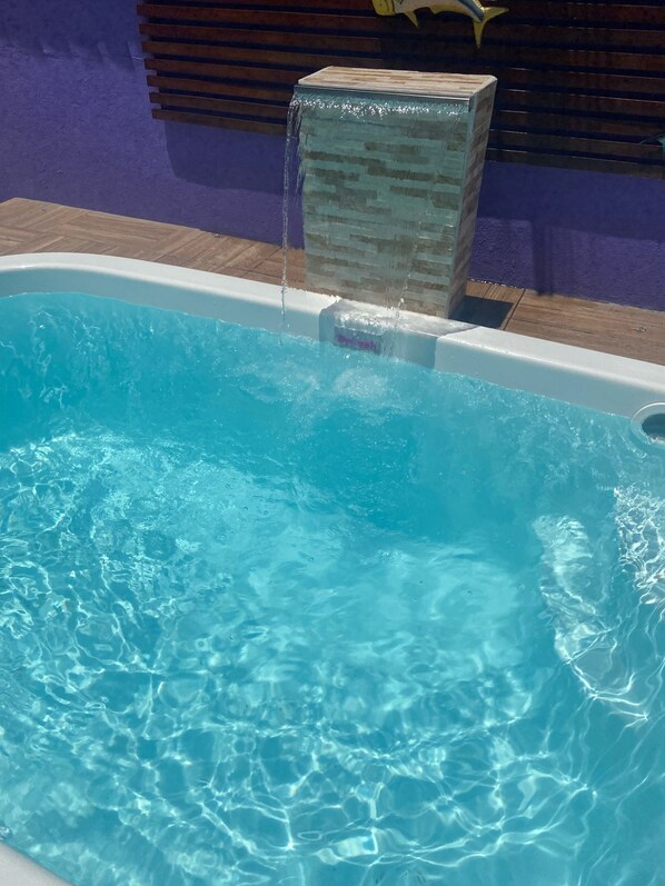 Una piscina con agua azul cristalina y una fuente.