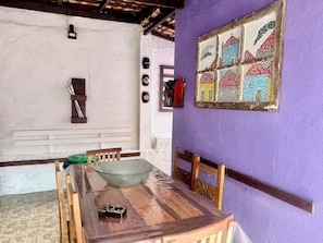 Enjoy meals in this cozy dining area with a wooden table, colorful artwork, and a patterned tile floor.