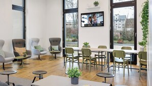 Een moderne kantoorruimte met een lange tafel, verschillende stoelen en een televisie aan de muur.