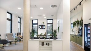 Een moderne kantoorruimte met een receptiebalie, zithoek en kitchenette.