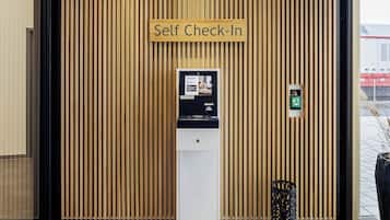 Un kiosque d’enregistrement automatisé avec un panneau en bois en arrière-plan et une enseigne au-dessus.