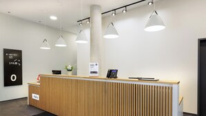 Een receptiebalie met een houten paneelontwerp, een zwarte telefoon en een bord met daarop 'Hello'.