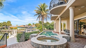 Un área de piscina con jacuzzi, mobiliario de exterior y vistas a casas vecinas.
