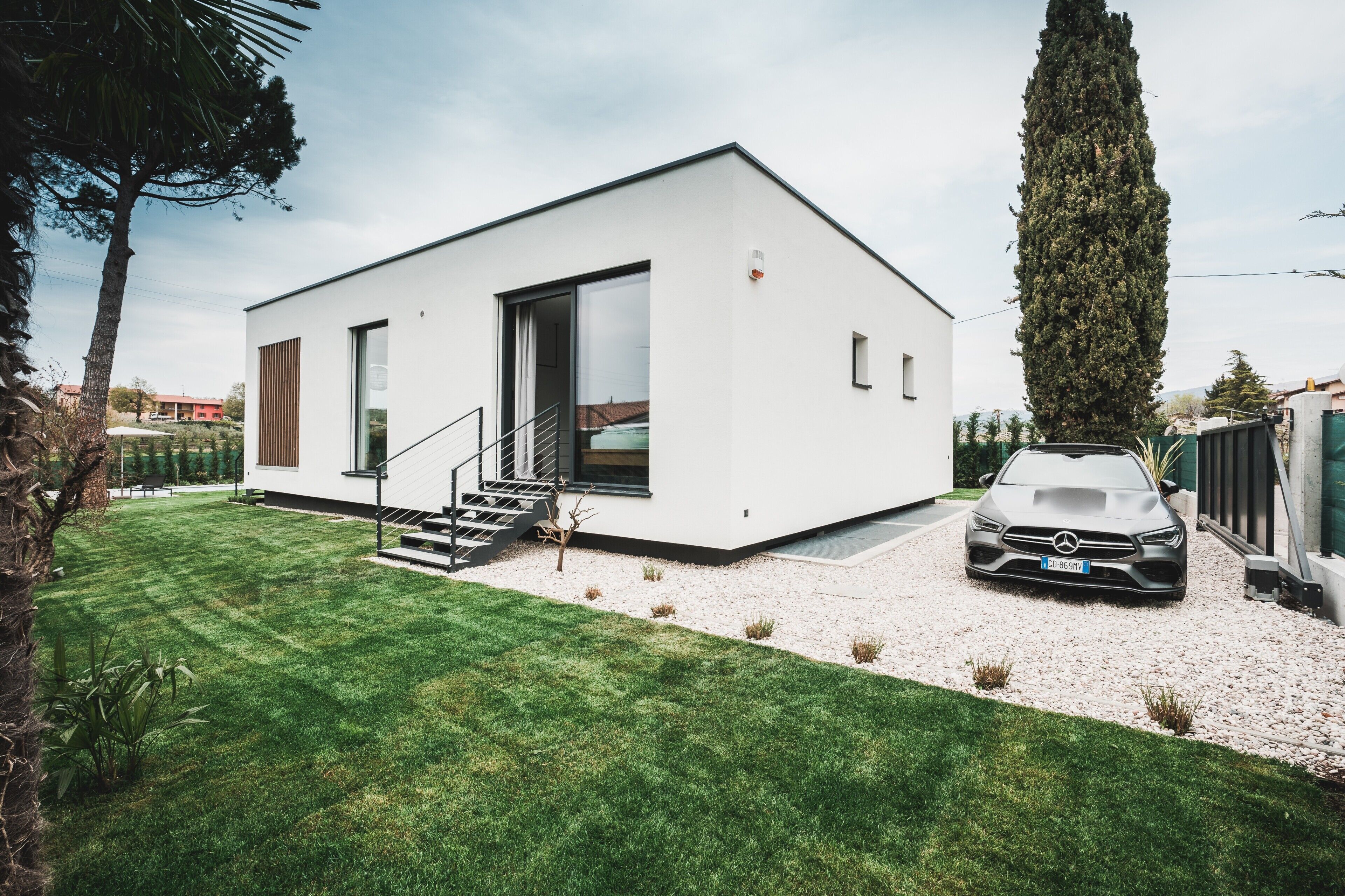 A modern single-story house with a white exterior, a driveway, and a parked car.