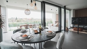 A dining area with a table set for two, a bottle of wine, and a bowl of pasta. - Modern Villa "Montelino Boutiquehouse " with Pool, Wi-Fi, Air Conditioning & Terrace (Bardolino)