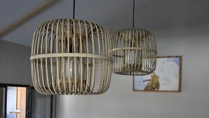 Una habitación con un sofá de mimbre, un banco de madera y dos lámparas colgantes de mimbre.