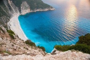 A coastal landscape with a beach, rocky cliffs, and a clear blue sea. - Sailing Yacht by Owner, Holidays to Greek Islands (Alimos)