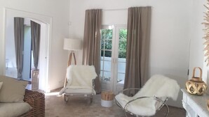 Un salón amplio con sofá, dos sillones, una lámpara y vistas al exterior a través de un ventanal.