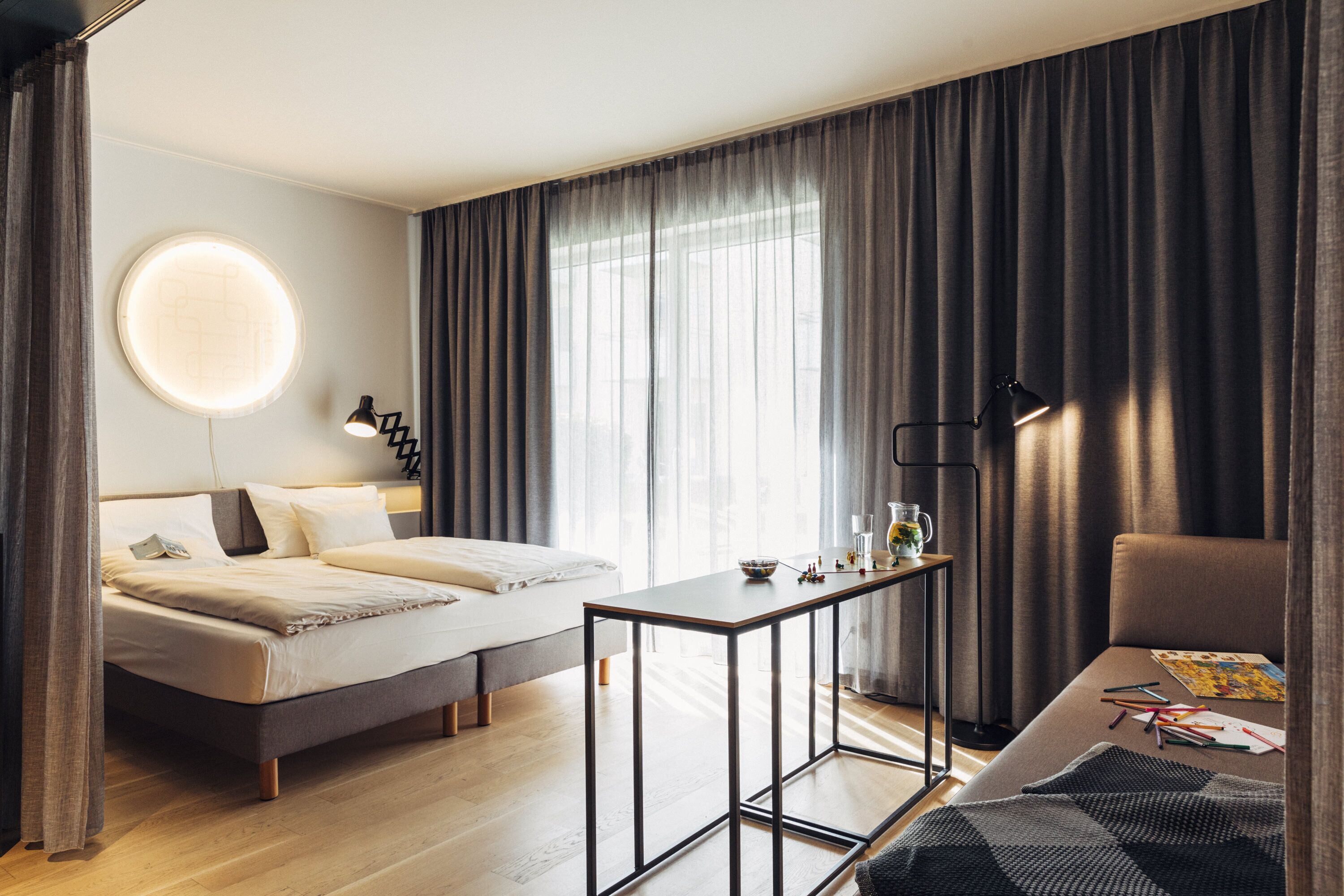 A modern hotel room with a bed, a small table, and a chair.