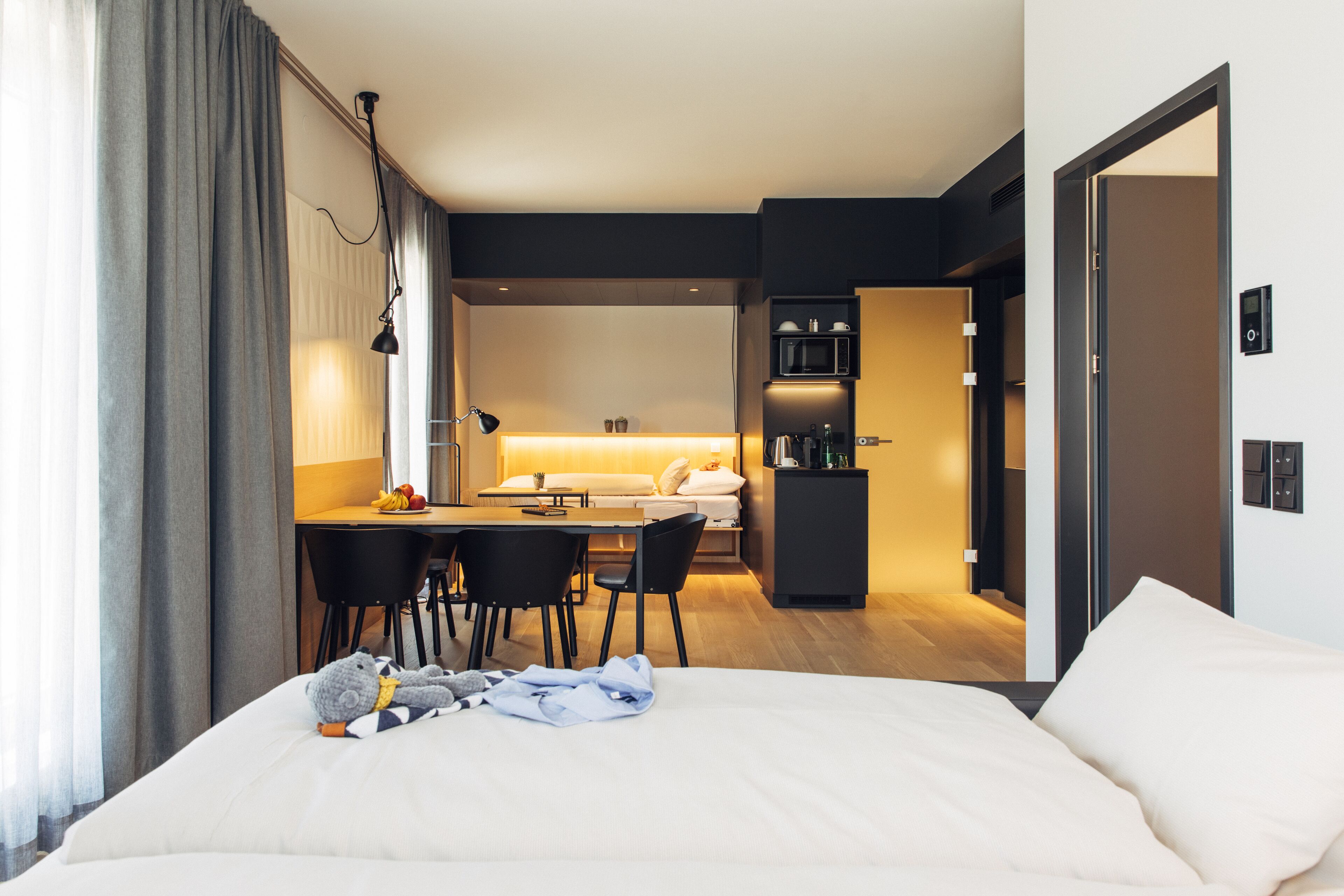 A hotel room with a bed, a desk, and a kitchenette.