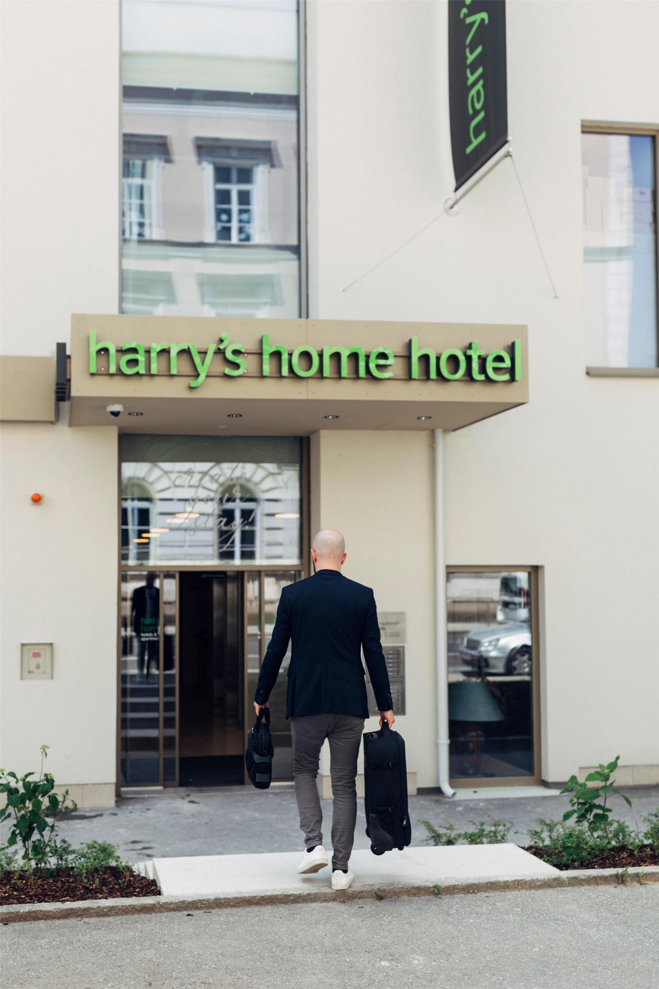 A man walking towards Harry's Home Hotel, carrying a briefcase and a bag.