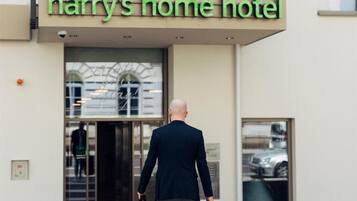 A man walking towards Harry's Home Hotel, carrying a briefcase and a bag.