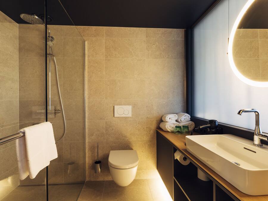 A modern bathroom with a glass shower enclosure, a toilet, a sink with a mirror, and a towel rack.