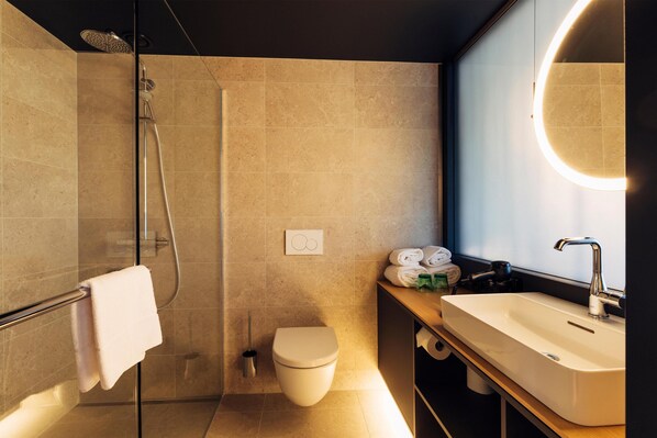A modern bathroom with a glass shower enclosure, a toilet, a sink with a mirror, and a towel rack. - harry’s home Steyr hotel & apartments (Steyr)