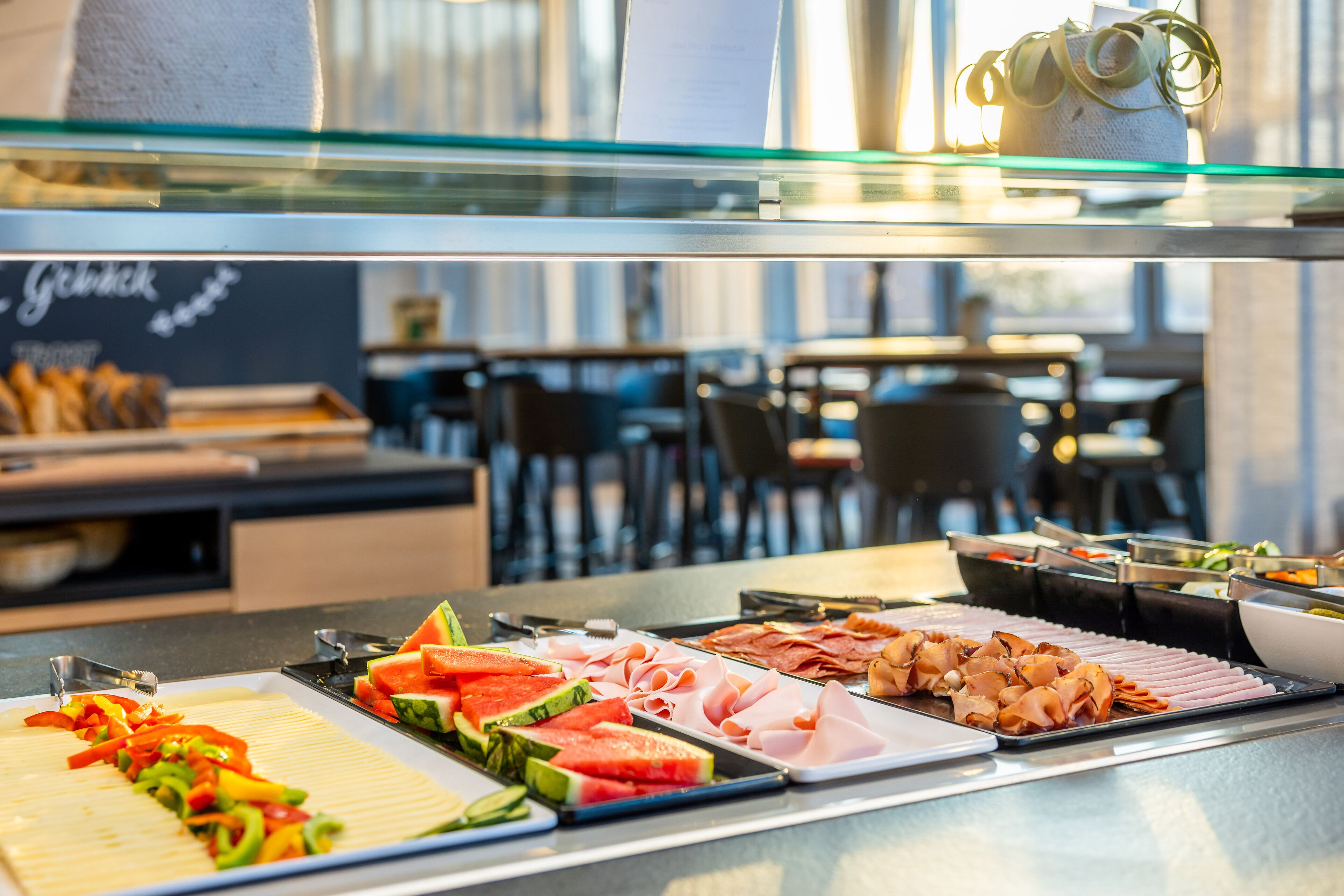 A buffet with various food items including sliced watermelon, vegetables, and meats.