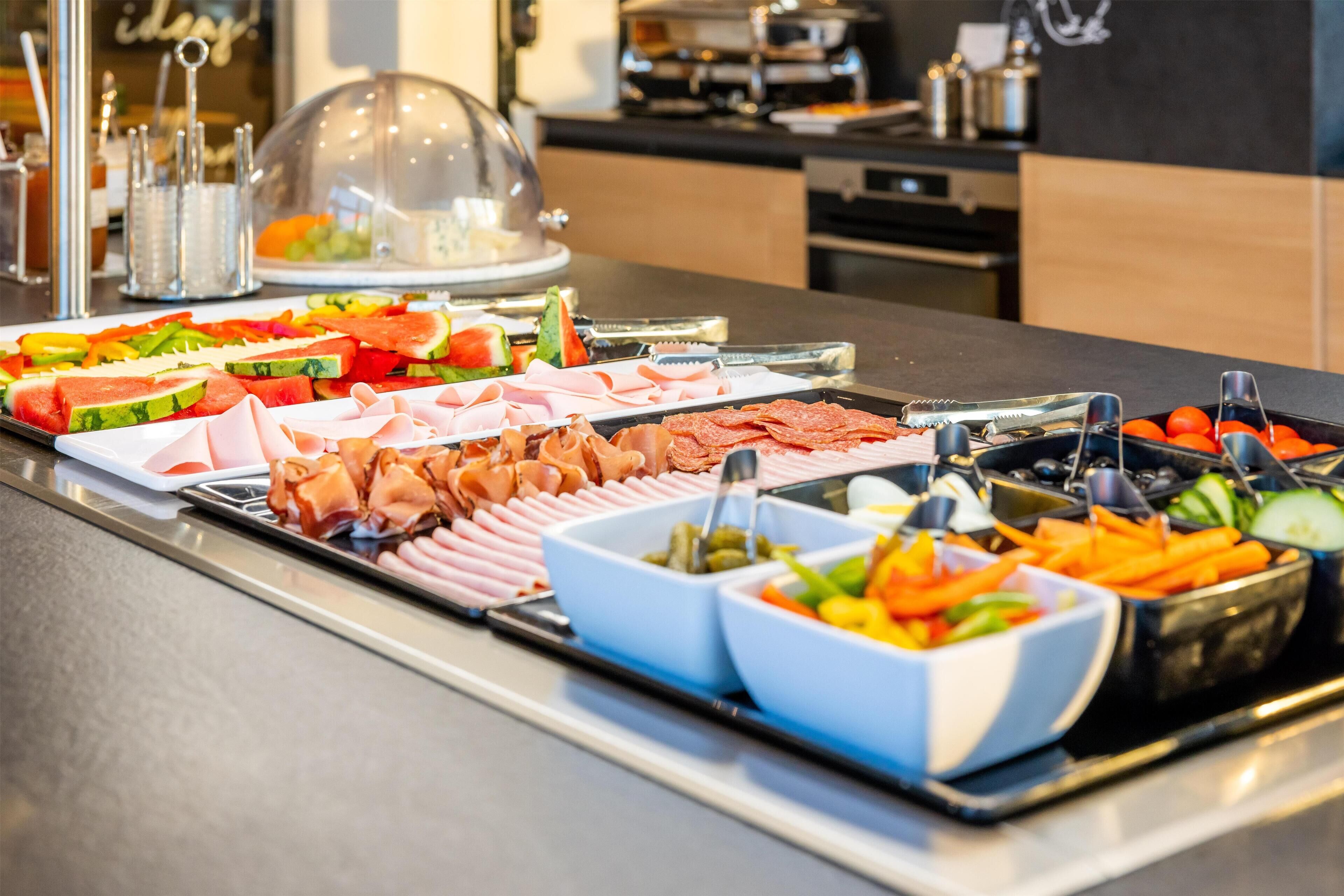 A buffet with various food items including fruits, vegetables, and meats.
