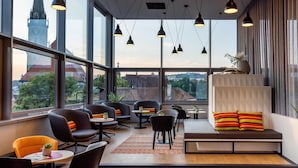 A modern interior with large windows, multiple seating areas, and pendant lighting. - harry’s home Steyr hotel & apartments (Steyr)