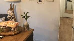 Une pièce avec un bureau en bois, une lampe, une plante et un mur orné de tableaux.