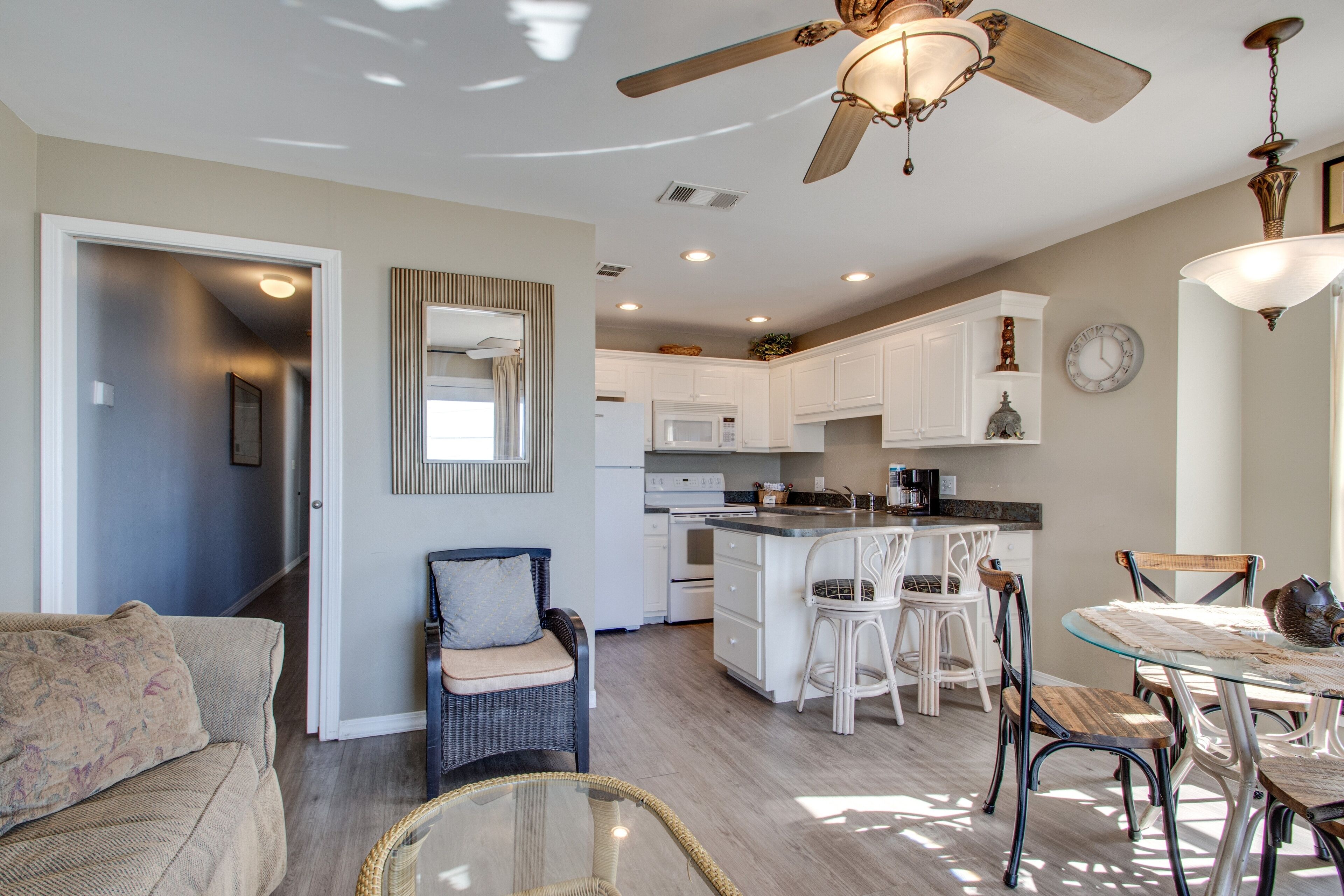 A spacious kitchen with white cabinets, a central island with bar stools, and a dining table with chairs.
