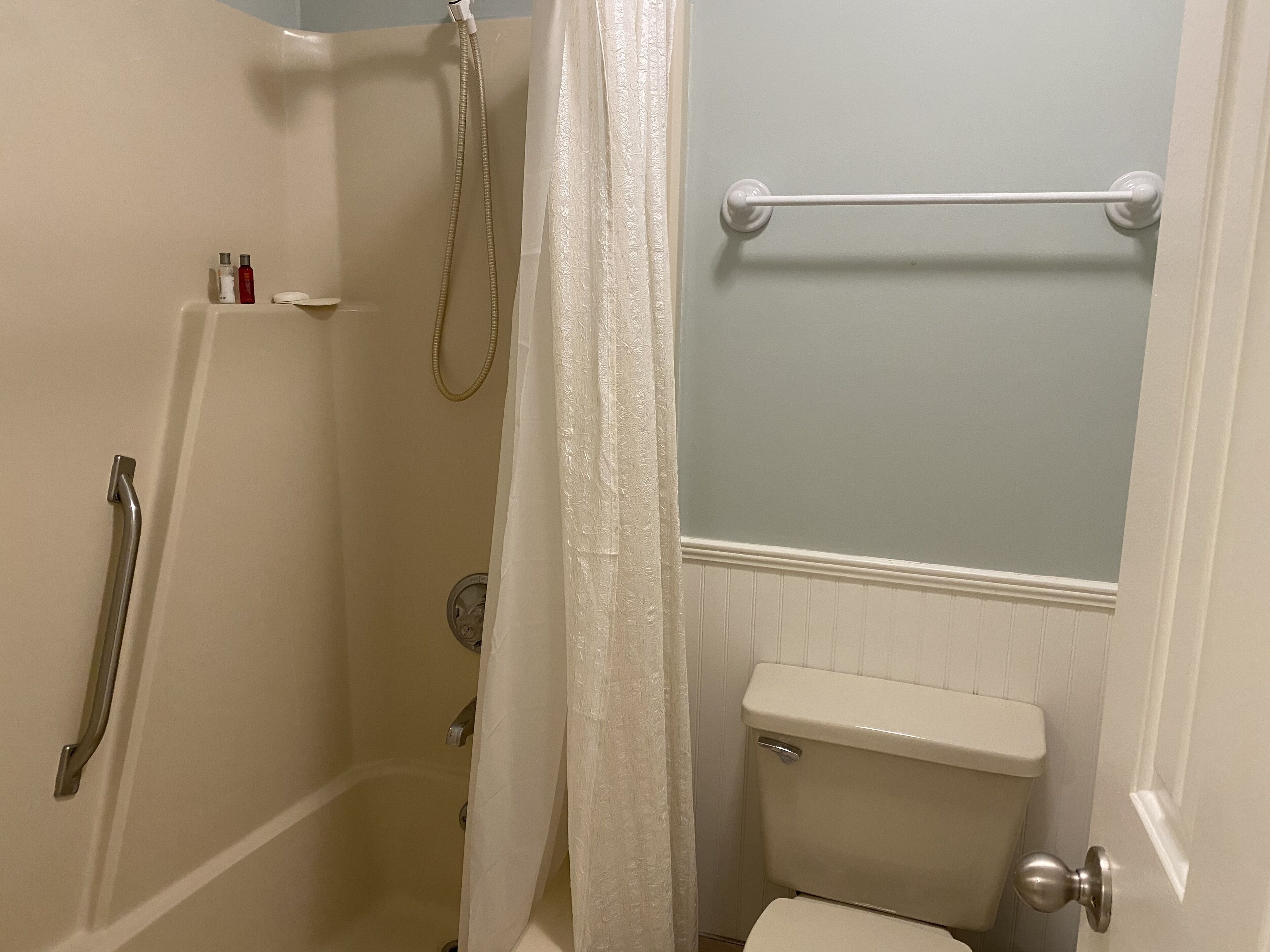 Baño con ducha, inodoro y toallero.