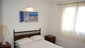 A bedroom with a bed, a nightstand, a lamp, a painting on the wall, and a window with curtains. - PRIVATE Villa with Pool/WIFI/PARKING - Villa Alba, Villa Alba In L'Escala - $ Bedrooms, Pool, WIFI (L'Escala)