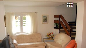 A living room with a beige sofa, a television, and a staircase. - PRIVATE Villa with Pool/WIFI/PARKING - Villa Alba, Villa Alba In L'Escala - $ Bedrooms, Pool, WIFI (L'Escala)