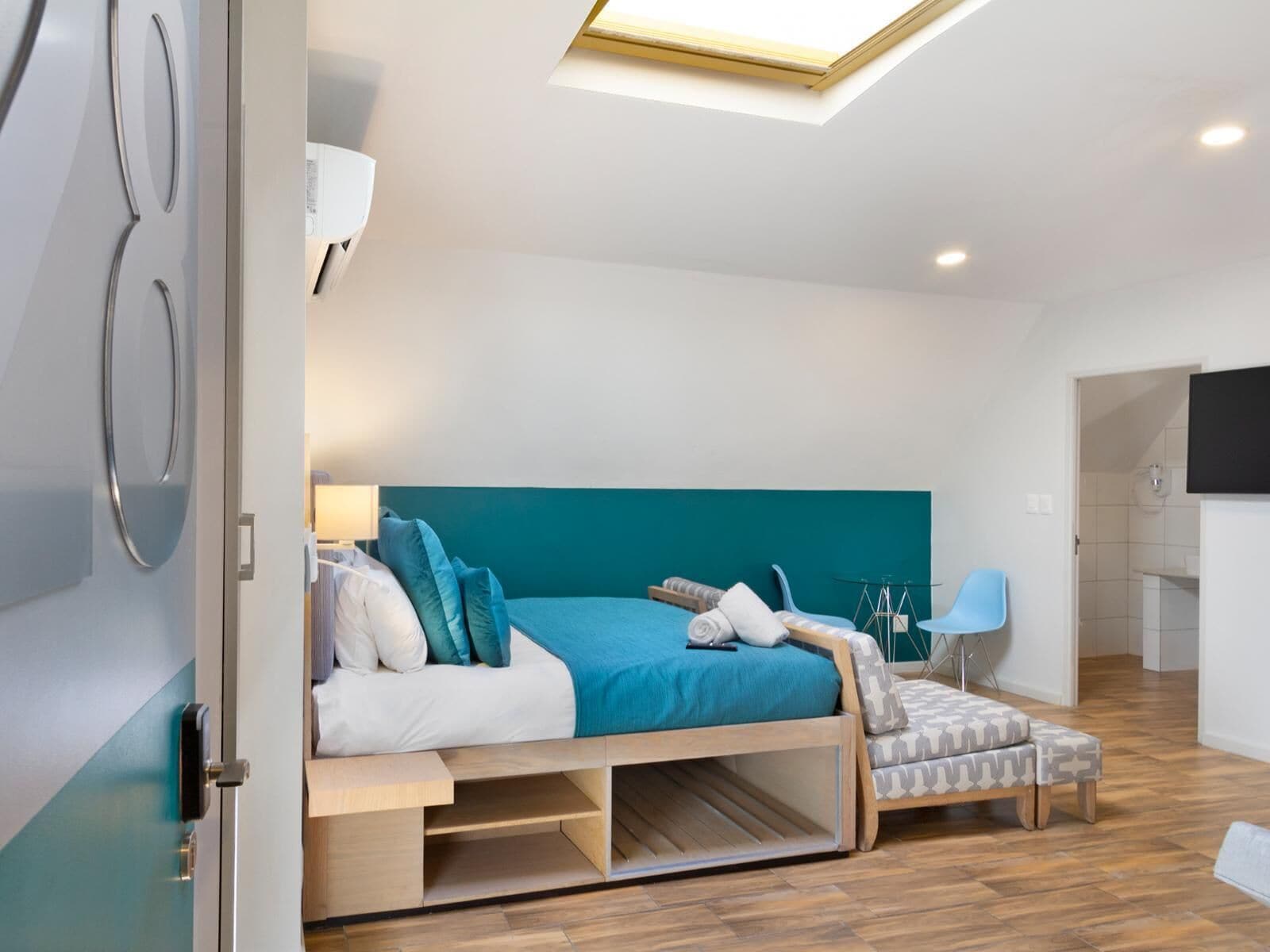 Une chambre moderne avec un lit, un bureau, une chaise et un téléviseur.