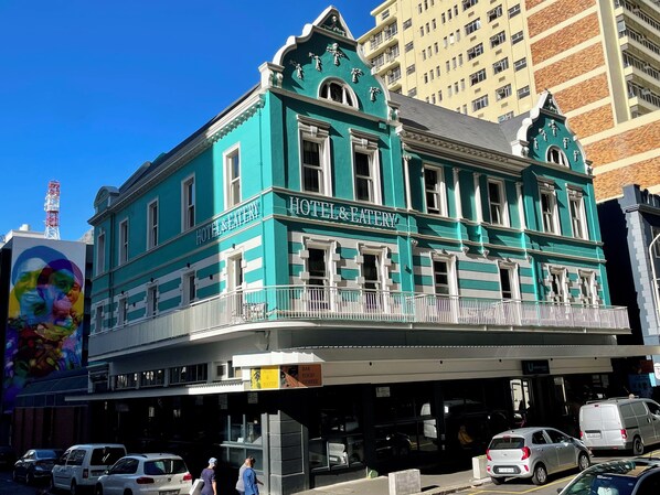 Classic hotel with a bar, food, and coffee on the ground floor, offering a balcony with a railing.