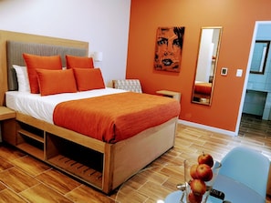 Relax in a stylish room with a comfortable bed, large mirror, and a small table with a vase of fresh fruit.