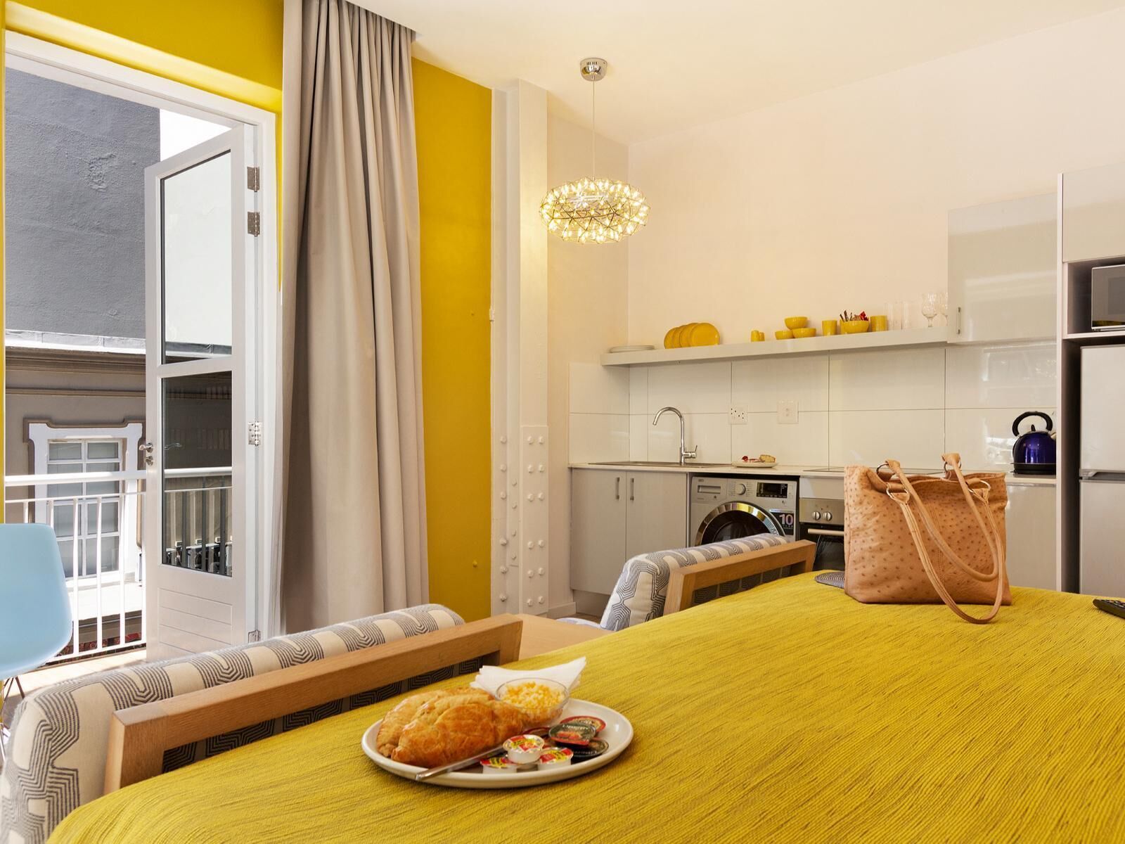 Hotelkamer met een bed, een eettafel met eten, een kitchenette en uitzicht.