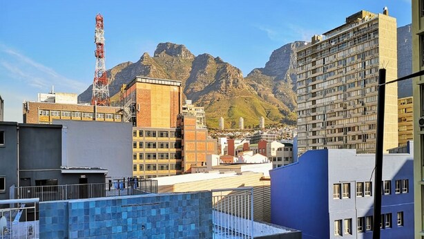 Una piscina en la azotea con vistas a montañas y edificios urbanos.