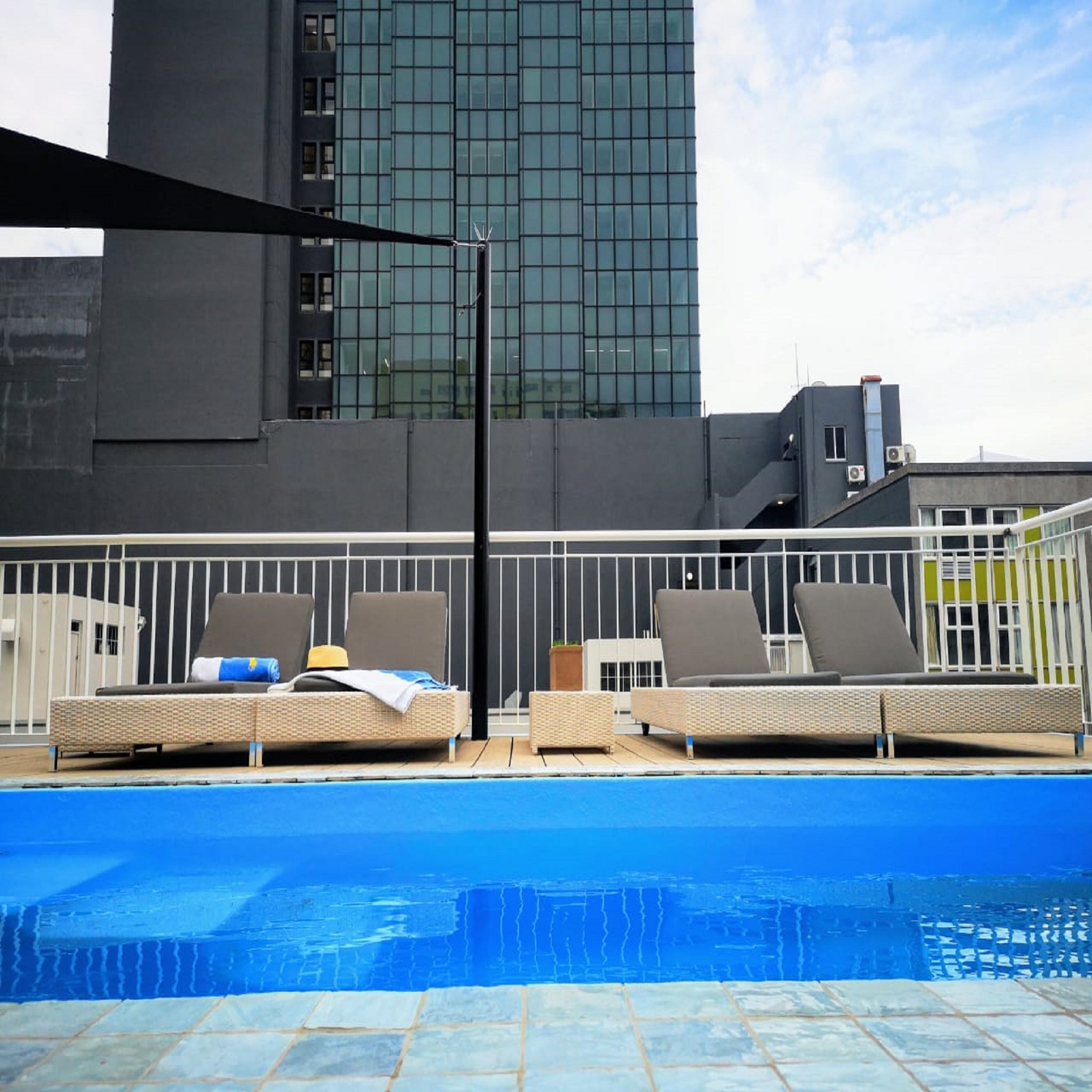 A rooftop pool with lounge chairs and a modern building in the background.