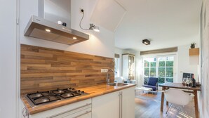 Una cocina moderna con salpicadero de madera, electrodomésticos de acero inoxidable y un comedor con vistas a zonas verdes.