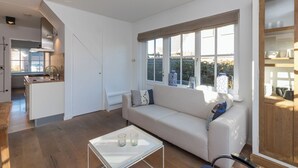 Una sala de estar moderna con un sofá, una mesa de centro y una cocina visible a través de una puerta abierta.