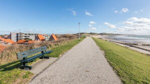 A gravel path leading to a beach with a bench and street lamps. - Apt - Duinweg 117-4 | Zoutelande 'Duinoo (Zoutelande)