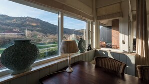 A room with a large window offering a view of a hilly landscape. There is a table with a lamp and two vases on it. - Apt - Duinweg 117-4 | Zoutelande 'Duinoo (Zoutelande)