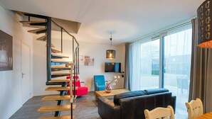 A modern living room with a staircase, a sofa, a coffee table, and a TV.